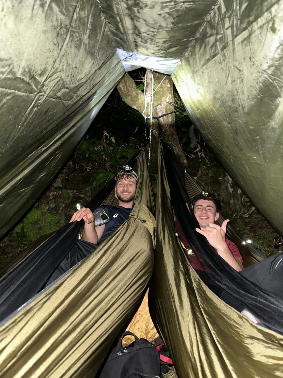 Zwei MOHANA Teilnehmer entspannen lachend in Hängematten unter einem Tarp im Regenwald der Azoren.